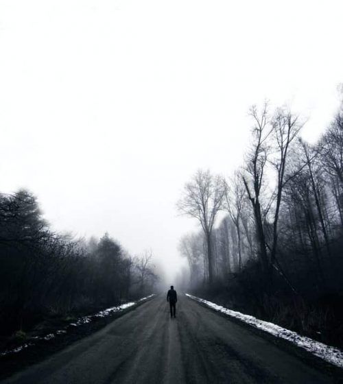 Hombre caminando solo por camino en medio de árboles