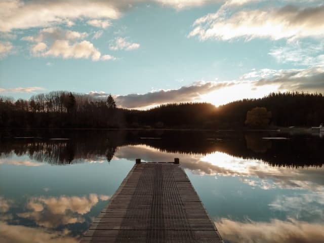 Puente de madera sobre lago con montañas delante