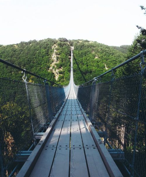 Puente colgante de madera entre montañas