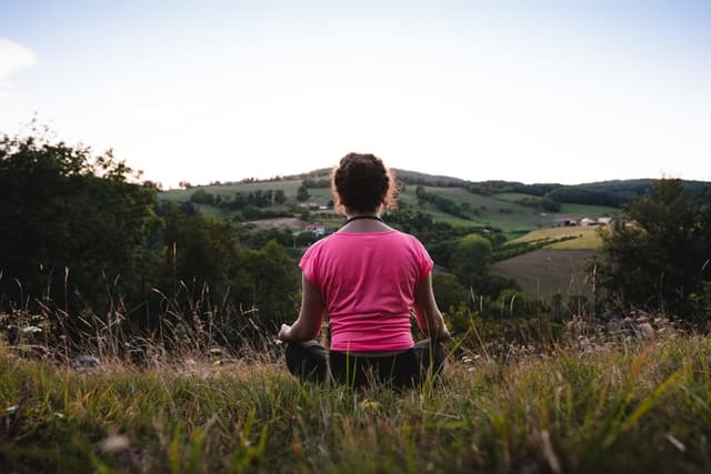 Mujer meditando sentada sobre la hierva